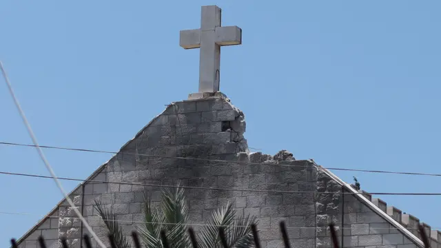 Damaged Gaza church with visible damage to roof next to cross