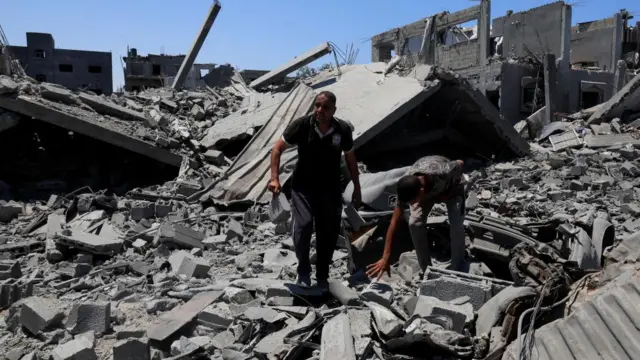 Palestinians inspect the damage on houses destroyed during an Israeli military operation, in Deir al-Balah, central Gaza Strip, July 23, 2025