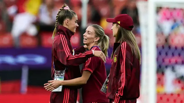 Germany's forward #15 Selina Cerci (L) and Germany's midfielder #20 Elisa Senss (C) embrace as they walk on the pitch with Germany's midfielder #20 Elisa Senss (R)