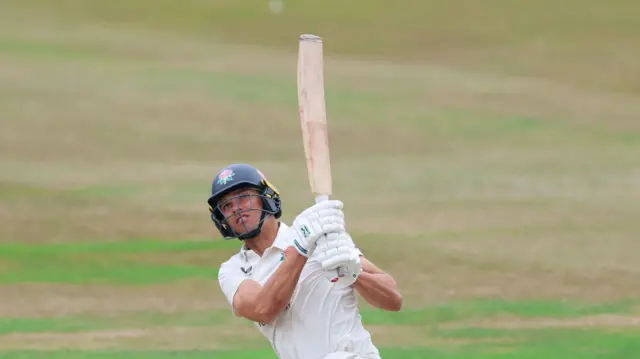 Chris Green on his knees looking upwards as he hits a shot towards midwicket
