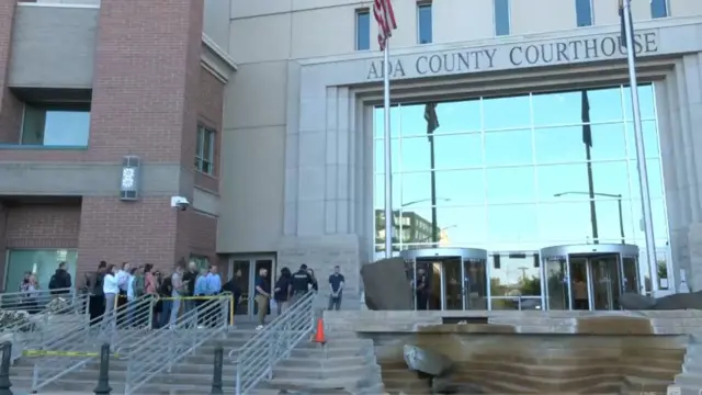 The exterior of the courthouse which has two revolving doors, a glass frontage, with stairs cornered off. There is a queue of people on the left hand side