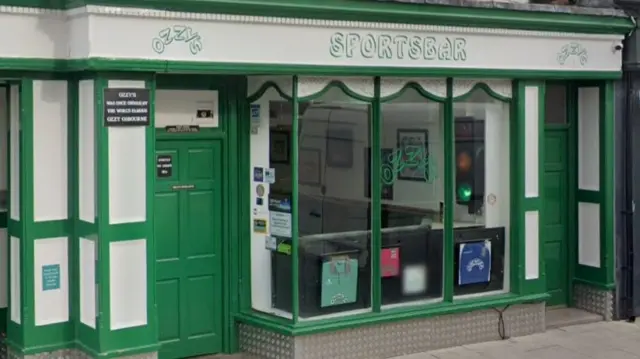 A green and white frontage onto a high street with "Ozzy's Sportsbar" in green stencilling above the windows