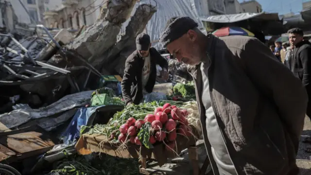 A man peers down at vegetables in an open-air market in Gaza.