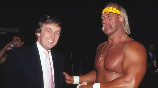 Donald Trump in a suit stands next to a shirtless Hulk Hogan
