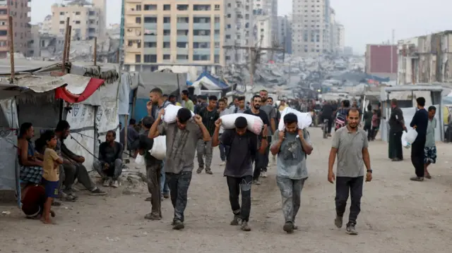Palestinians carry aid supplies on Tuesday after trucks loaded with aid entered from Israel through central Gaza