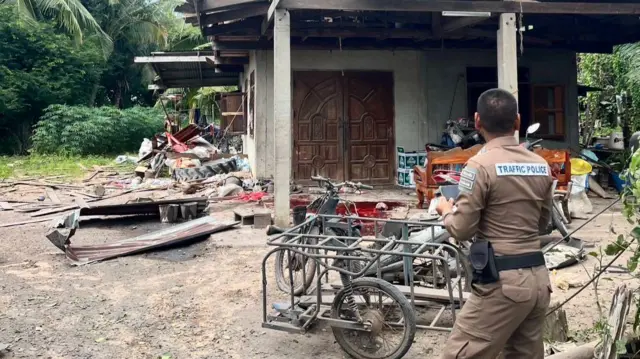 A police officer inspects a damaged house