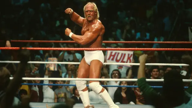 Hulk Hogan poses in the centre of the ring, flexing his muscles, in a match from the 80s.