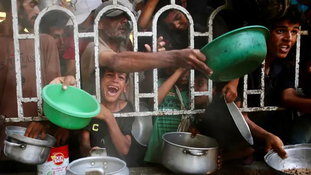 Palestinians shove to receive a hot meal at a charity kitchen in the Mawasi area of Khan Yunis in southern Gaza.