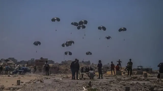 People on the ground look up as aid is airdropped over parts of Gaza