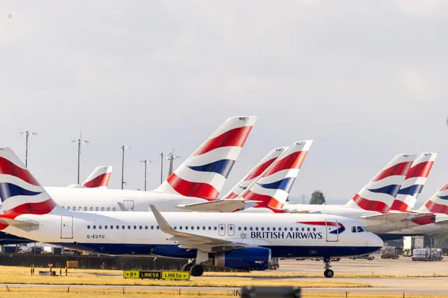 A row of British Airways passenger planes on the tarmac of an airport