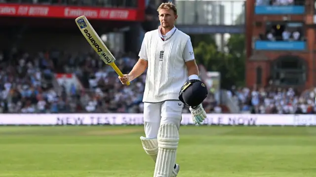 Joe Root holding his bat and helmet after exiting the pitch after getting 150 runs at Old Trafford.