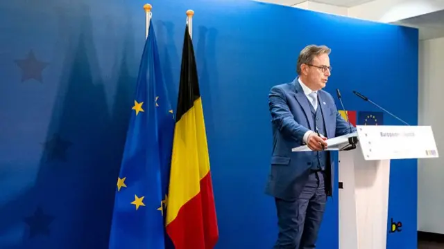 The Belgian prime minister to the right of the EU and Belgian flags