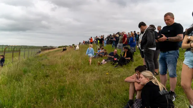People gather on the grassy verges outside prestwick airport amid Trump's arrival