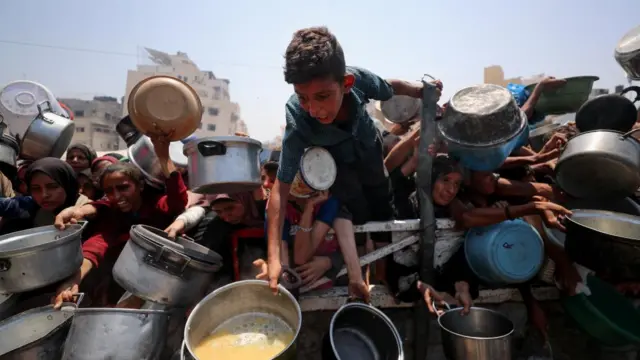 Palestinians wait to receive food from a charity kitchen