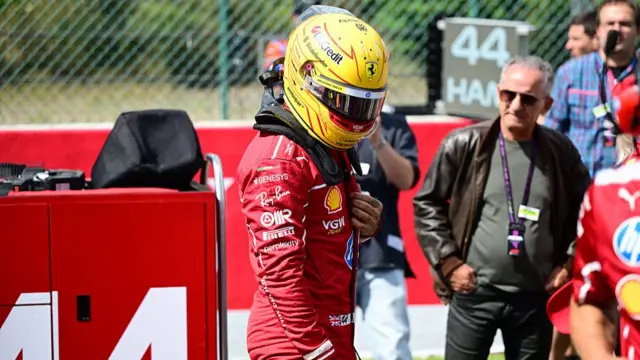 Lewis Hamilton stands outside his car with his helmet on at Spa.
