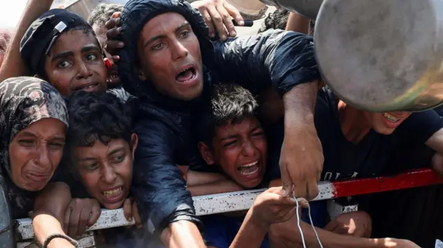 Palestinians wait to receive food from a charity kitchen