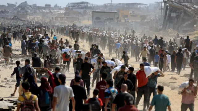 Palestinians gather as they carry aid supplies that entered Gaza through Israel