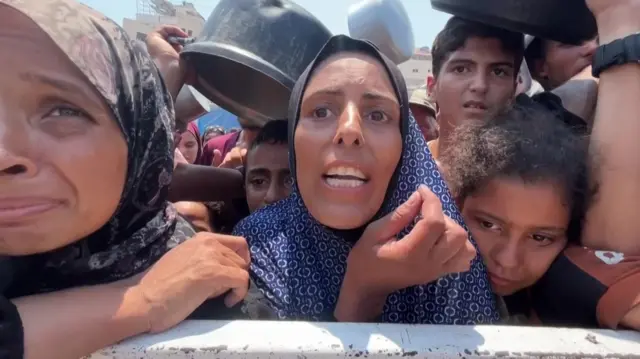 Umm Abdallah Al-Sharafy amid a crowd of Gazans hoping for food