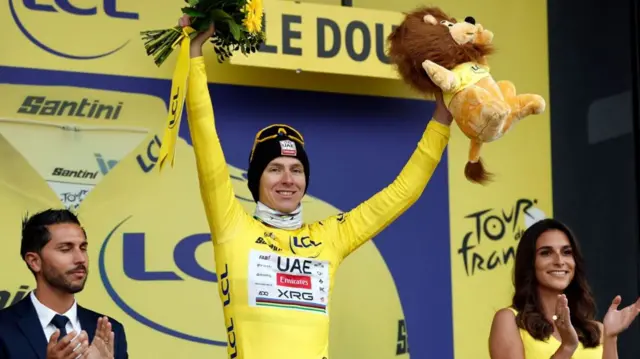 Tadej Pogacar with his arms aloft on the podium after stage 20 of the 2025 Tour de France