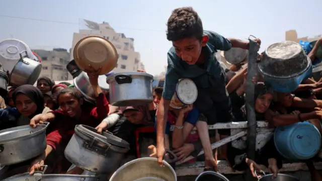 Palestinians wait to receive food from a charity kitchen, amid a hunger crisis, in Gaza City