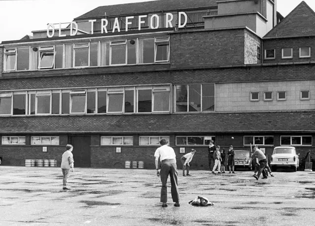A group of young boys play a game of cricket outside Old Trafford, ahead of the upcoming Ashes Test match between England and Australia in 1964