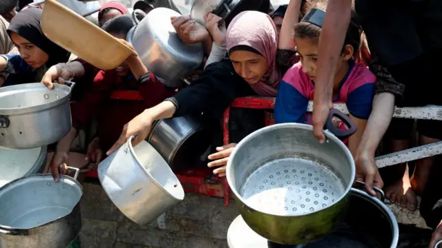 Palestinians wait to receive food from a charity kitchen
