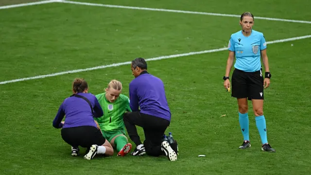 Hannah Hampton of England receives medical treatment, as Referee Stephanie Frappart looks on