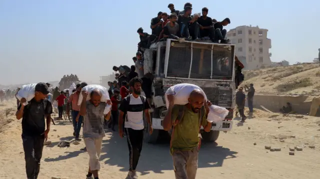 Palestinians carry aid supplies that entered Gaza through Israel, in Beit Lahia in the northern Gaza Strip