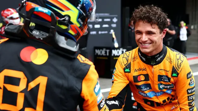 Lando Norris shakes the hand of his teammate Oscar Piastri.