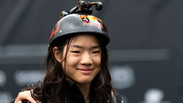 A fan with a Red Bull hat with a toy Red Bull car on the top.