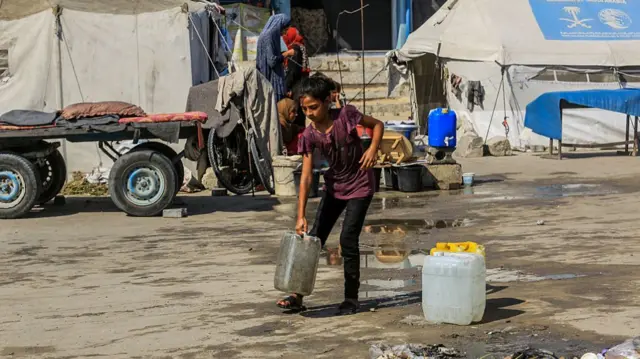 A child carries a water tub in Khan Younis