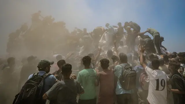Gazans in dust trying to get aid from truck