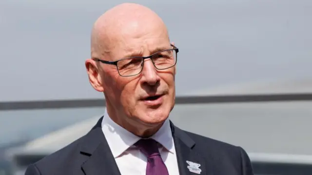 John Swinney in glasses, suit and purple tie