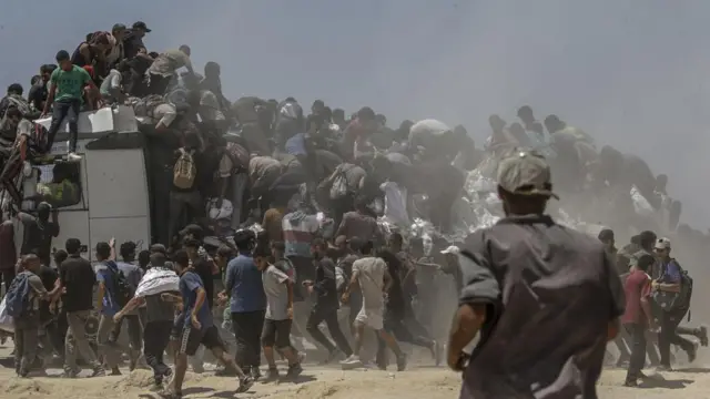 A large crowd of people climb on a lorry
