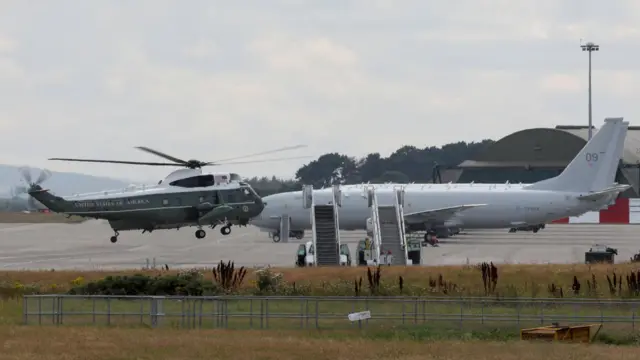 A US helicopter and a white plane are seen together on an airfield in Scotland.