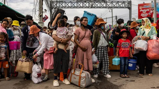 Cambodian migrant workers wait to cross a checkpoint in Thailand in droves on Monday
