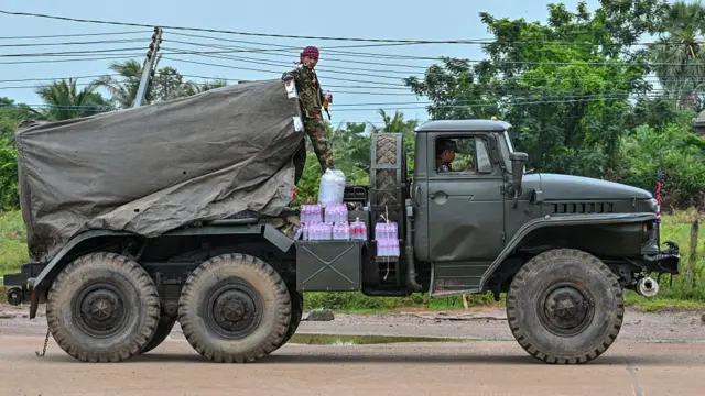 A Cambodian soldier stands on a truck carrying a Russian-made BM-21 rocket launcher travelling along a street in Oddar Meanchey province