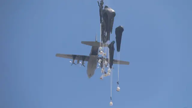 Aid being dropped out of the back of an aircraft - pallets are falling through the sky with parachutes attached