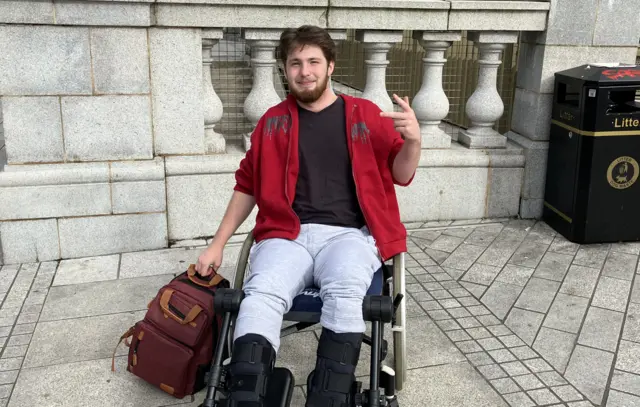 Miko Zdunski sits in a wheelchair looking up towards the camera