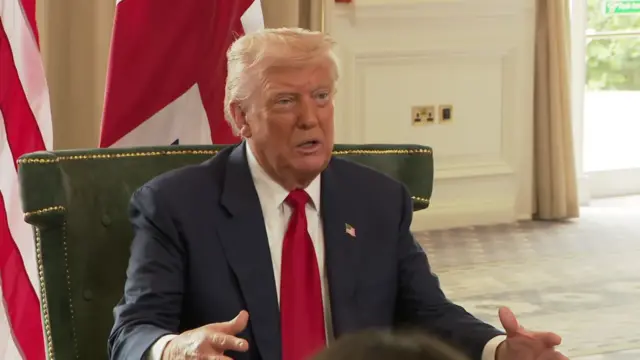 Trump sitting down in suit with red tie