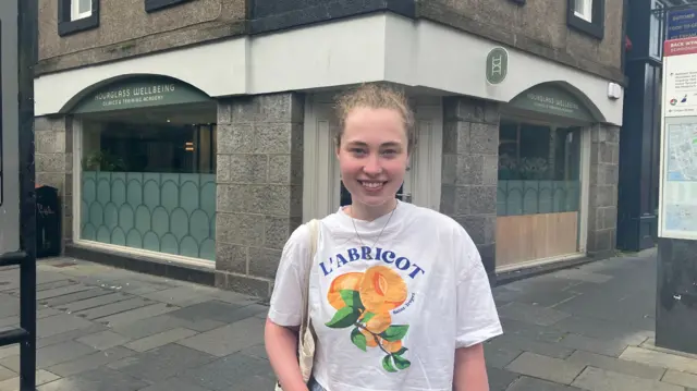 Beth MacDonald stands and smiles at the camera