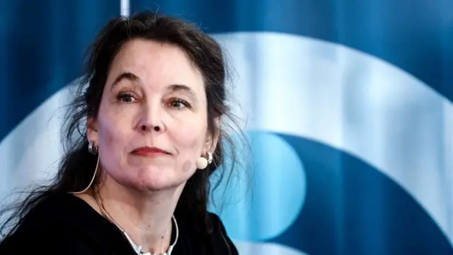 Sigrid De Vries, a woman with dark hair, is pictured with a mic in a black top