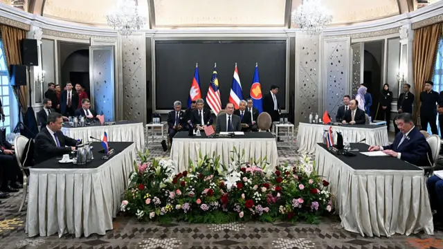wide shot of a room with officials sitting at rectangular tables