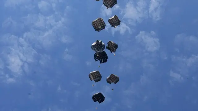 Several aid packages dropped from a plane in central Gaza via parachutes against the blue sky