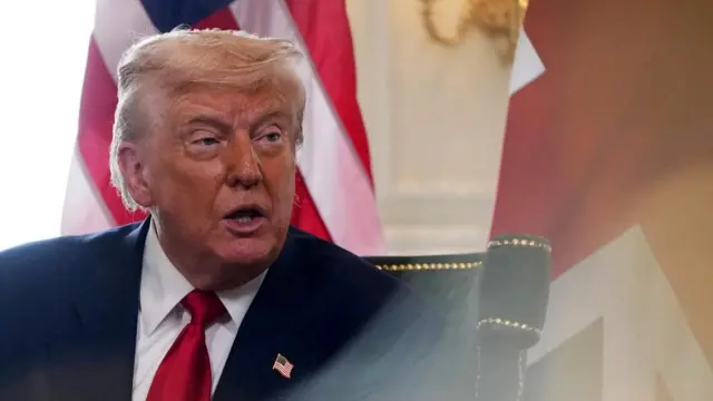 Trump seated in a chair with the UK flag behind him as he speaks in Scotland