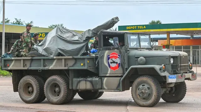 Cambodian soldiers stand on a military truck with an anti-aircraft gun in Oddar Meanchey province