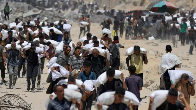 People carrying bags of aid on their shoulders