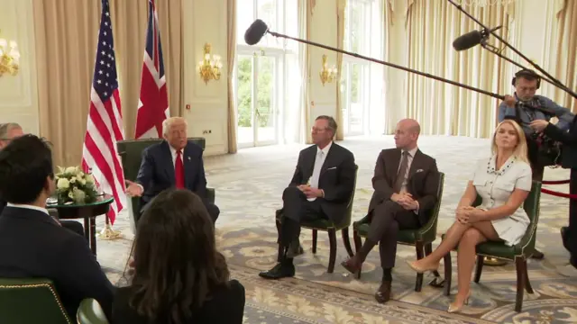 Donald Trump in suit and red tie in front of UK and US flags