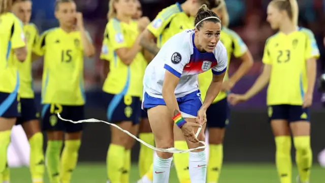 Lucy Bronze of England removes the tape from her leg before stepping up to take the team's seventh penalty in the penalty shoot out during the UEFA Women's EURO 2025 Quarter-Final match between Sweden and England at Stadion Letzigrund