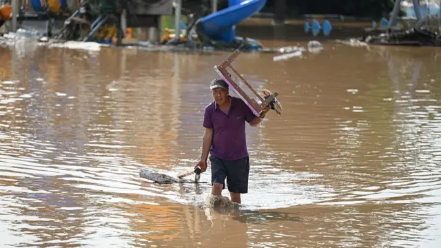 A resident carrying a table walks through a flooded area after heavy rains at Taishitun village in Miyun district, on the outskirts of Beijing on 28 July